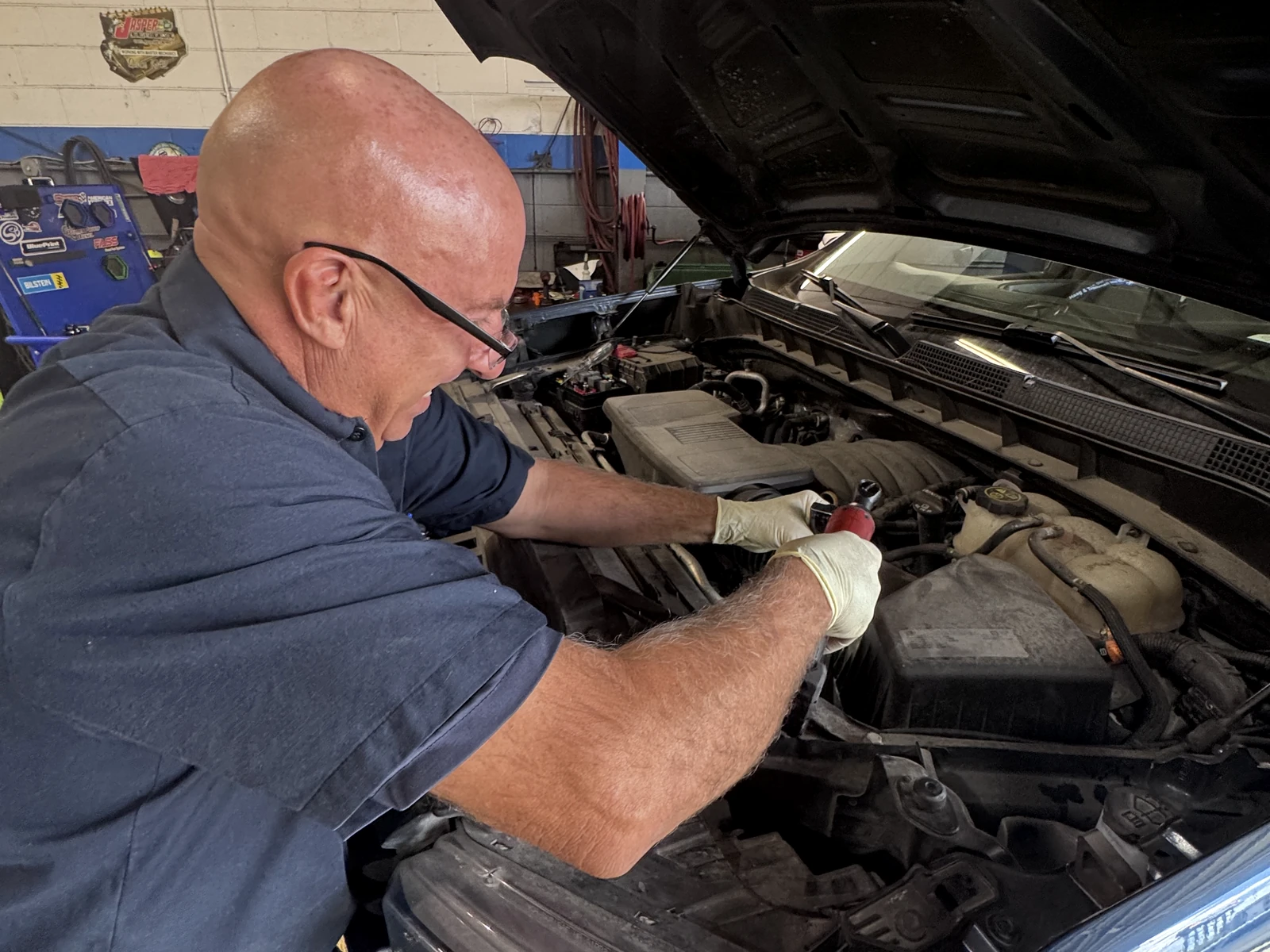 Allen’s Automotive technician actively working under the hood of a vehicle